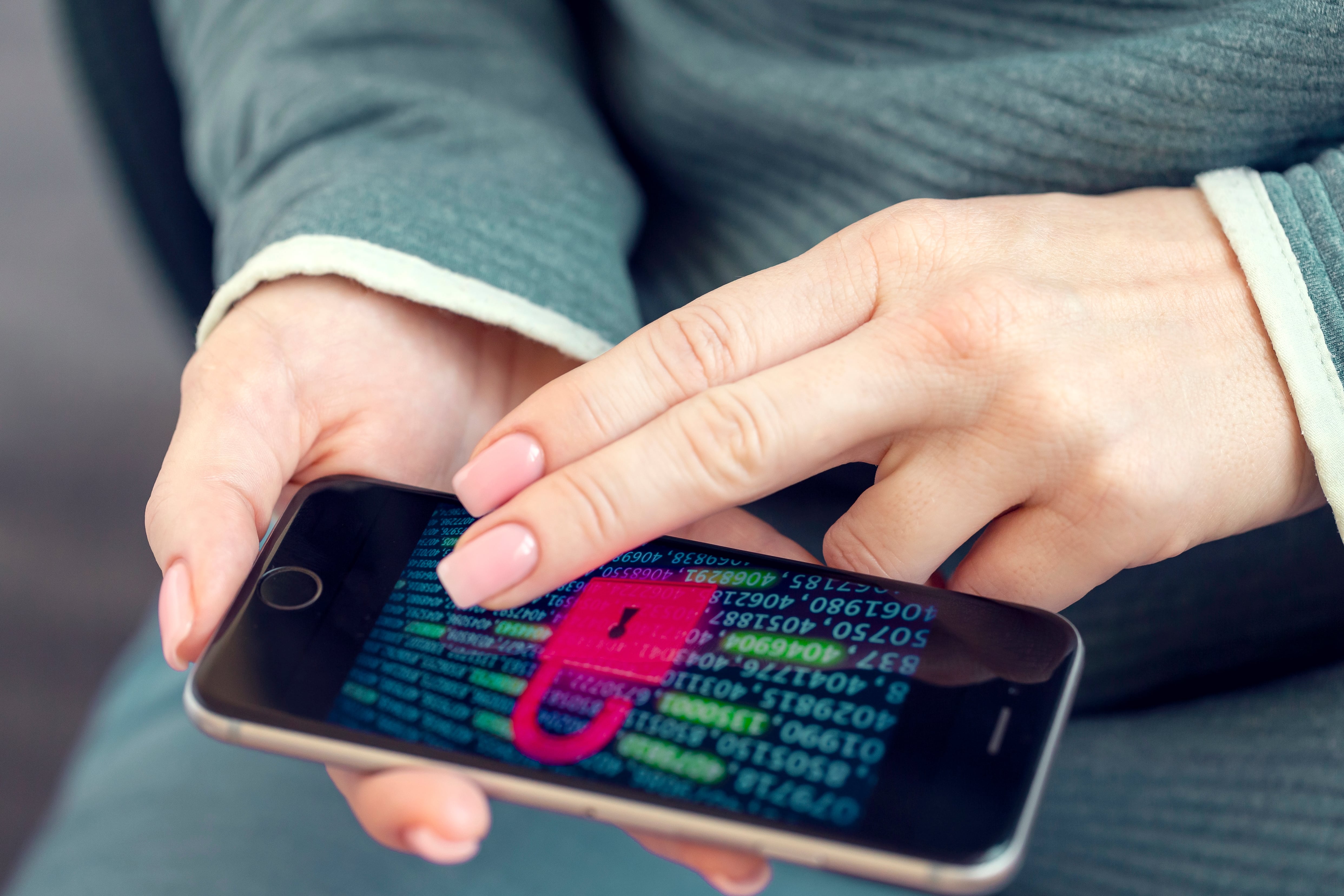 Des mains tiennent un cellulaire qui affiche un grand cadenas à l’écran.