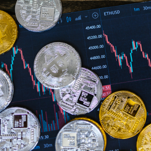Pièces de bitcoin et d’ether placées sur un écran affichant un graphique financier