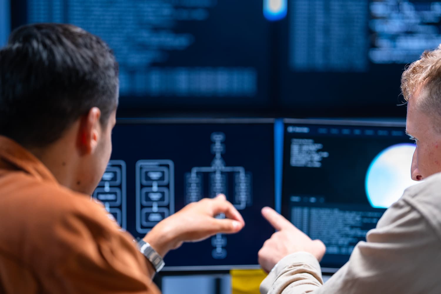 Des professionnels de la cybersécurité examinent des schémas de réseau et des données système sur plusieurs écrans d’ordinateur.